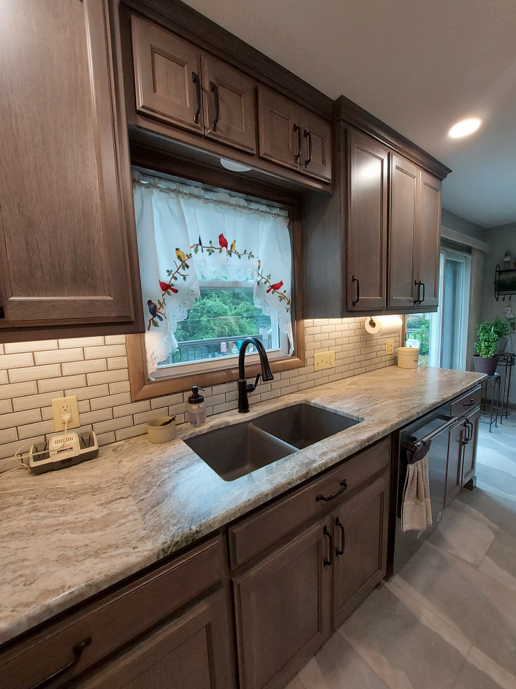 Mid-sized mountain style u-shaped ceramic tile and gray floor eat-in kitchen photo with a drop-in sink, dark wood cabinets, granite countertops, white backsplash, subway tile backsplash, stainless steel appliances and beige countertops