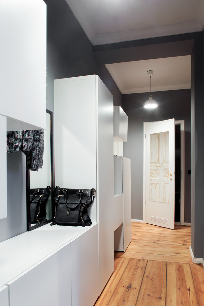 Inspiration for a small contemporary mudroom in Berlin with grey walls, medium hardwood floors and a white front door.