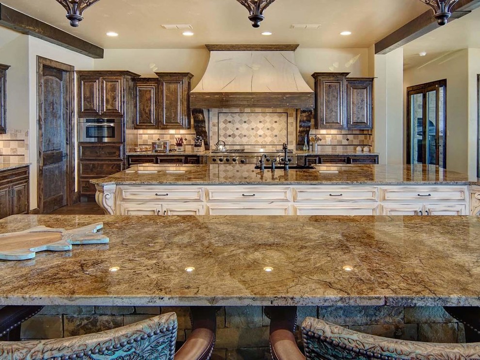 This is an example of an expansive country l-shaped open plan kitchen in Austin with recessed-panel cabinets, dark wood cabinets, granite benchtops and multiple islands.