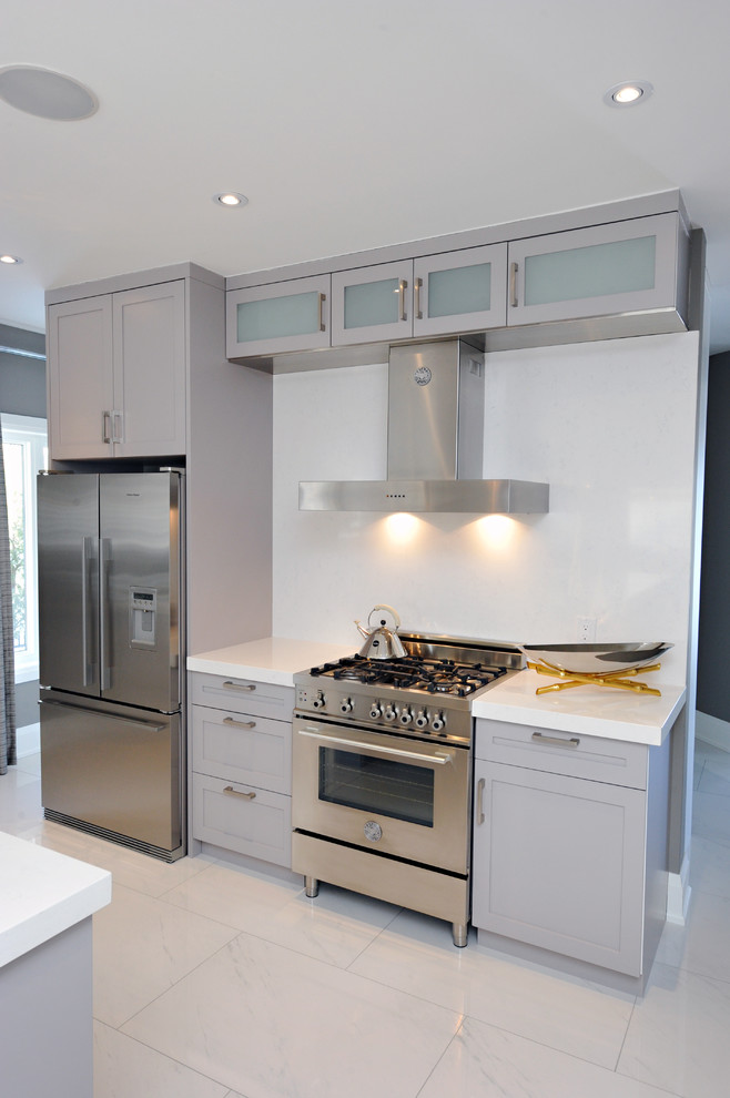 Inspiration for a mid-sized transitional l-shaped porcelain tile kitchen pantry remodel in Toronto with a double-bowl sink, shaker cabinets, gray cabinets, quartz countertops, white backsplash, stone slab backsplash, stainless steel appliances and an island