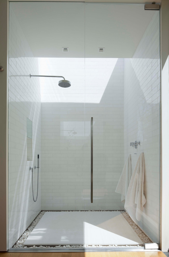 Photo of a contemporary bathroom in New York with an alcove shower, white tile, white walls and a hinged shower door.
