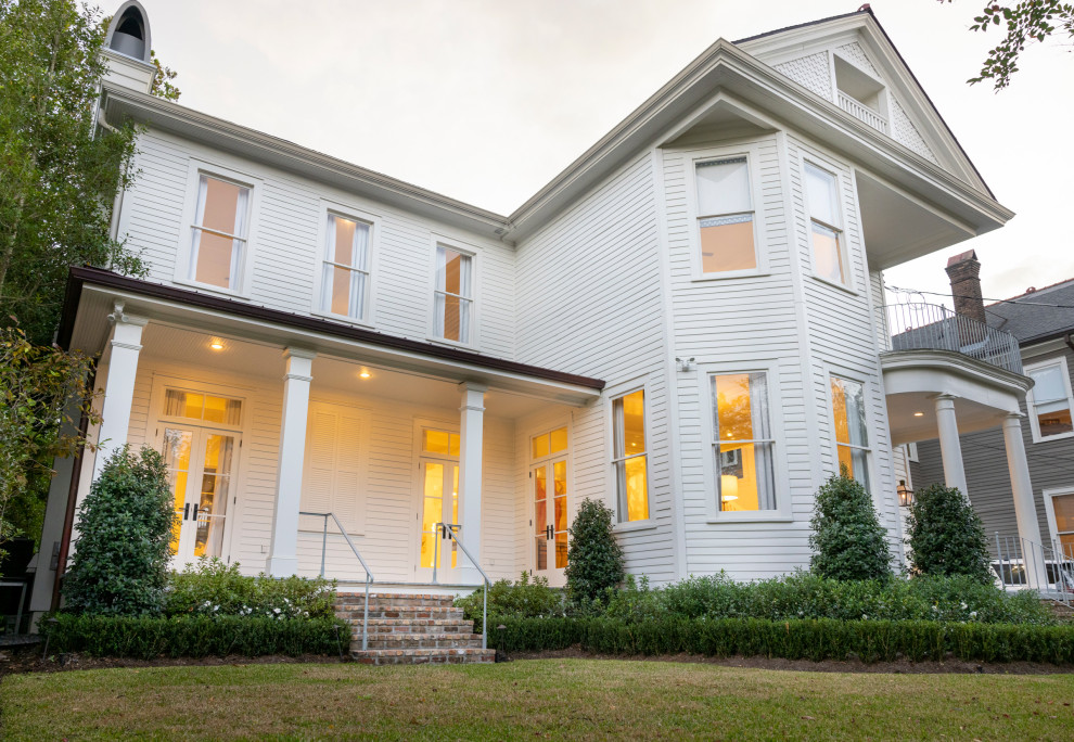 Photo of a large traditional two-storey white house exterior in New Orleans with a gable roof and wood siding.