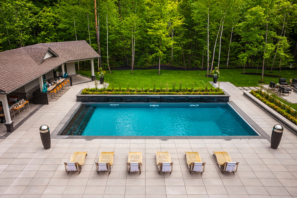 Design ideas for a large transitional backyard rectangular pool in Toronto with a water feature and concrete slab.