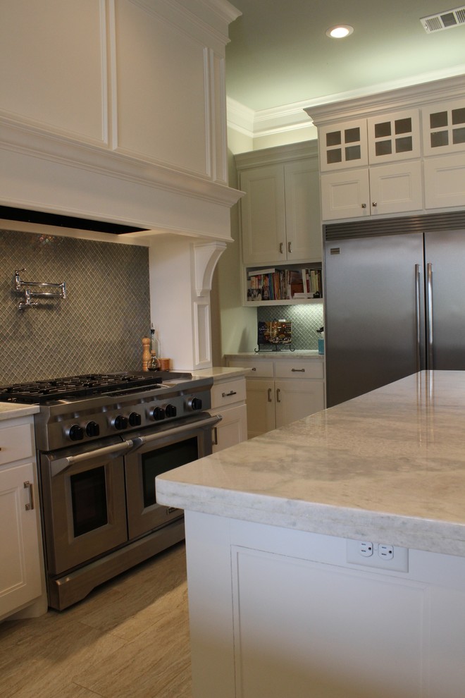 Kitchen - mid-sized transitional galley travertine floor kitchen idea in Austin with glass-front cabinets, white cabinets, granite countertops, green backsplash, mosaic tile backsplash, stainless steel appliances and an island