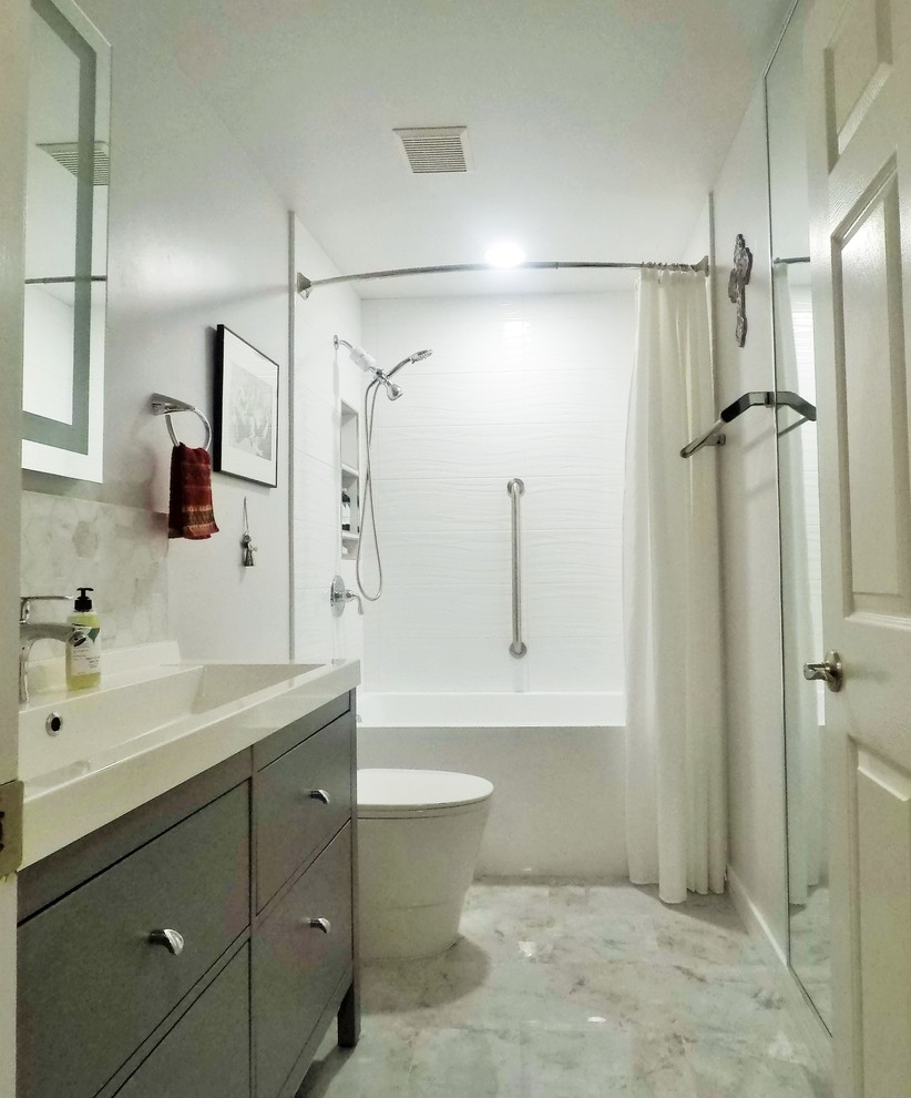 Photo of a mid-sized contemporary 3/4 bathroom in Other with flat-panel cabinets, grey cabinets, an alcove tub, a shower/bathtub combo, a one-piece toilet, white tile, ceramic tile, grey walls, porcelain floors, a trough sink, solid surface benchtops, grey floor, a shower curtain and white benchtops.