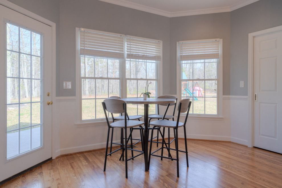 Inspiration for a mid-sized transitional galley medium tone wood floor eat-in kitchen remodel with an undermount sink, flat-panel cabinets, white cabinets, quartz countertops, white backsplash, subway tile backsplash, stainless steel appliances, an island and white countertops