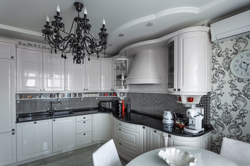 Inspiration for a mid-sized traditional u-shaped eat-in kitchen in Other with an undermount sink, raised-panel cabinets, white cabinets, solid surface benchtops, black splashback, mosaic tile splashback, black appliances, porcelain floors, no island, white floor and black benchtop.