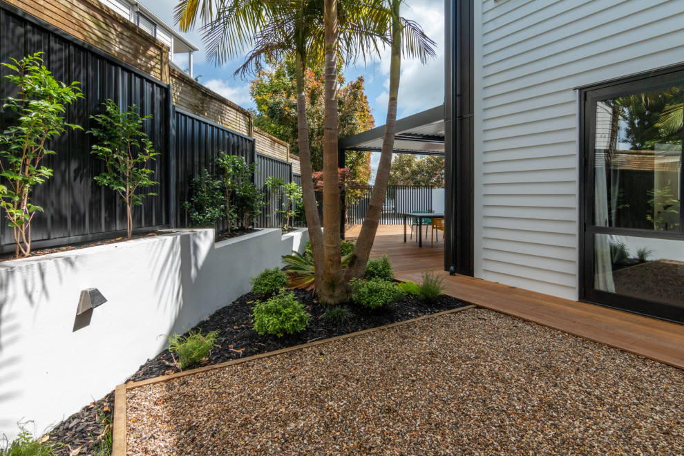 Halbschattiger Moderner Gartenweg neben dem Haus mit Sportplatz, Flusssteinen und Metallzaun in Auckland