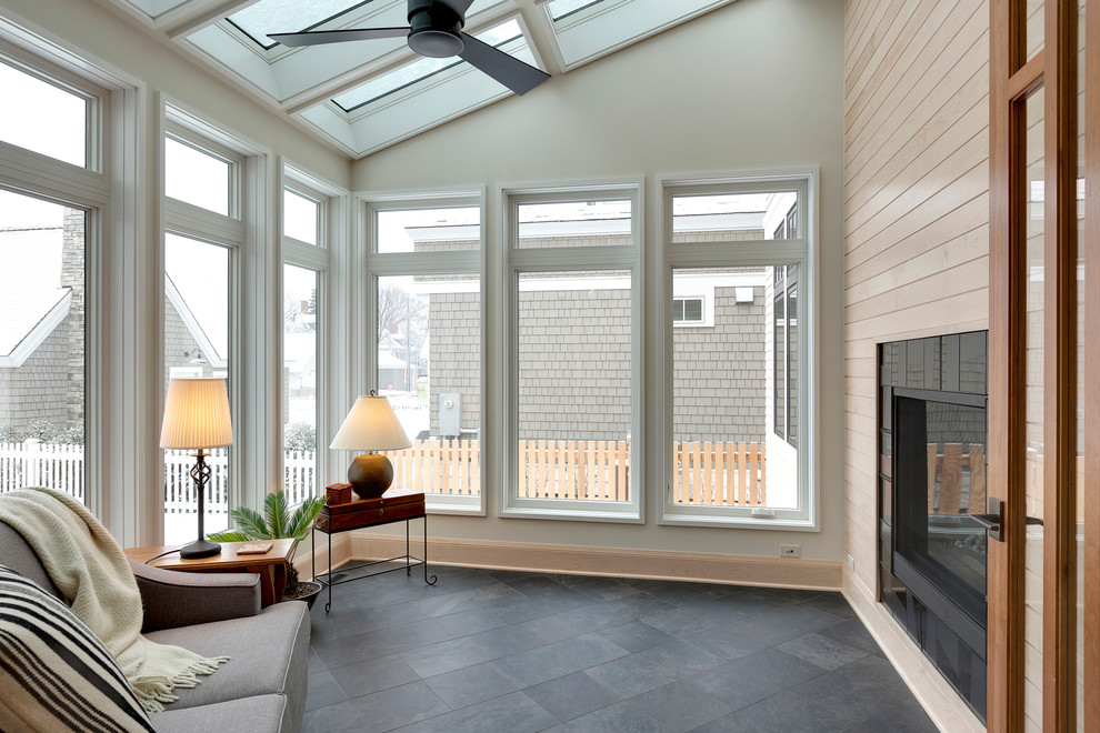 This is an example of a mid-sized transitional sunroom in Minneapolis with a two-sided fireplace, a tile fireplace surround, a skylight, ceramic floors and grey floor.