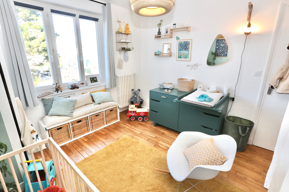 Aménagement d'une chambre de bébé neutre moderne de taille moyenne avec un mur vert et parquet clair.