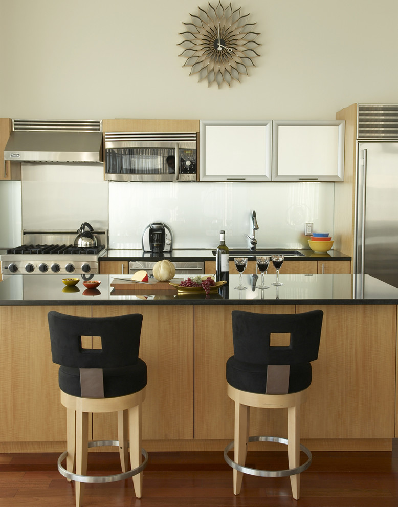 This is an example of a large modern single-wall eat-in kitchen in New York with stainless steel appliances, an undermount sink, flat-panel cabinets, medium wood cabinets, granite benchtops, grey splashback, medium hardwood floors and with island.