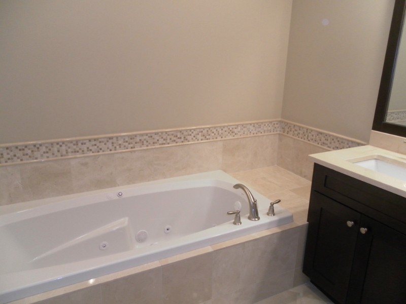 Example of a transitional brown tile alcove bathtub design in Chicago with an undermount sink, dark wood cabinets and beige walls