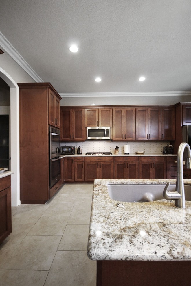 Kitchen - large transitional ceramic tile and beige floor kitchen idea with an undermount sink, shaker cabinets, medium tone wood cabinets, granite countertops, white backsplash, glass tile backsplash, stainless steel appliances, an island and brown countertops