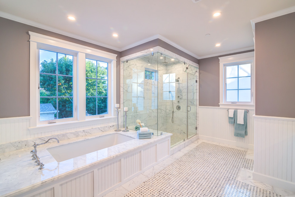 Photo of a large transitional master bathroom in Los Angeles with an undermount tub, white tile, marble, marble benchtops, white benchtops, an alcove shower, purple walls, mosaic tile floors, multi-coloured floor, a hinged shower door, shaker cabinets, white cabinets, a drop-in sink and a one-piece toilet.