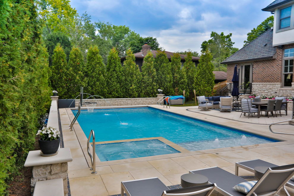 Photo of a mid-sized traditional backyard rectangular lap pool in Chicago with with privacy feature and natural stone pavers.
