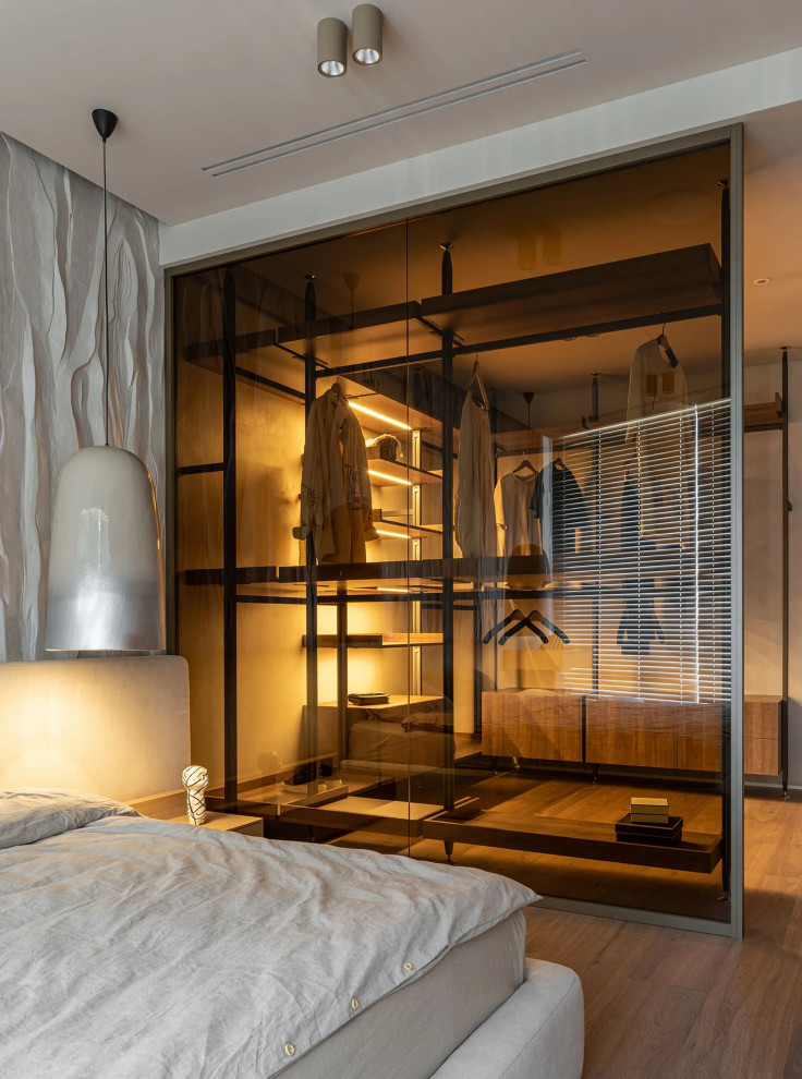 Imagen de armario vestidor unisex nórdico de tamaño medio con armarios tipo vitrina, puertas de armario de madera oscura, suelo de madera oscura y suelo marrón
