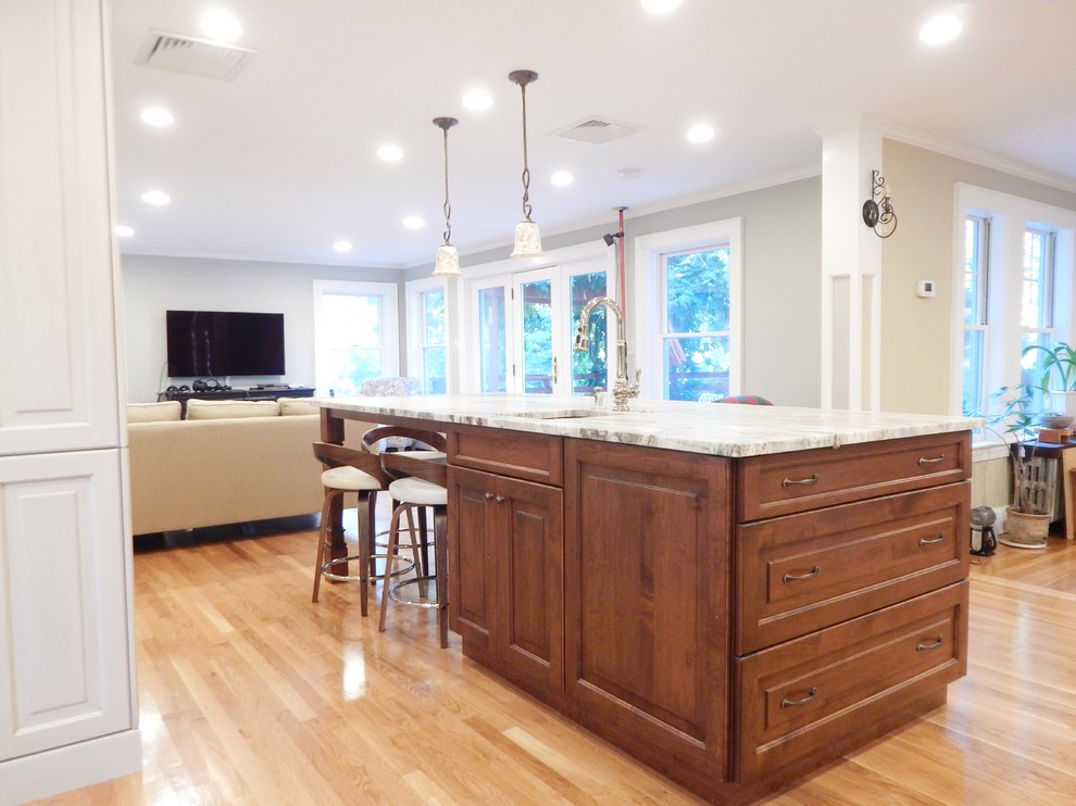 Example of a mid-sized transitional l-shaped light wood floor open concept kitchen design in Boston with an undermount sink, raised-panel cabinets, white cabinets, quartzite countertops, stainless steel appliances and an island