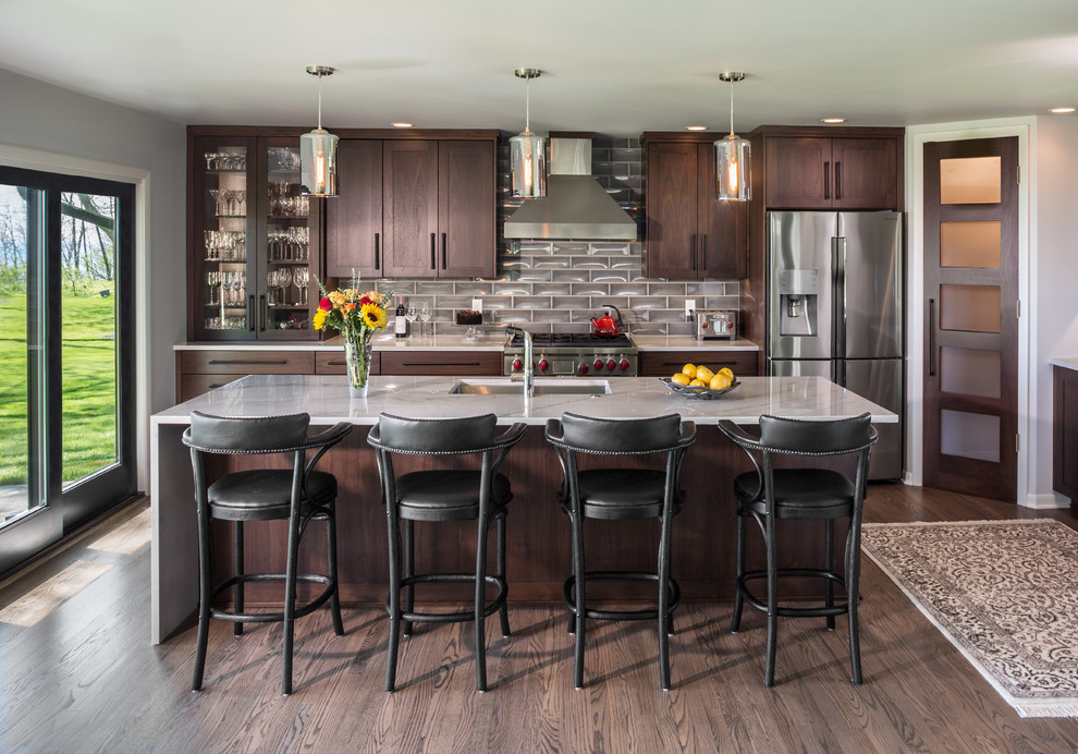 This is an example of a transitional kitchen in Milwaukee with an undermount sink, shaker cabinets, dark wood cabinets, grey splashback, stainless steel appliances, dark hardwood floors, with island and quartzite benchtops.