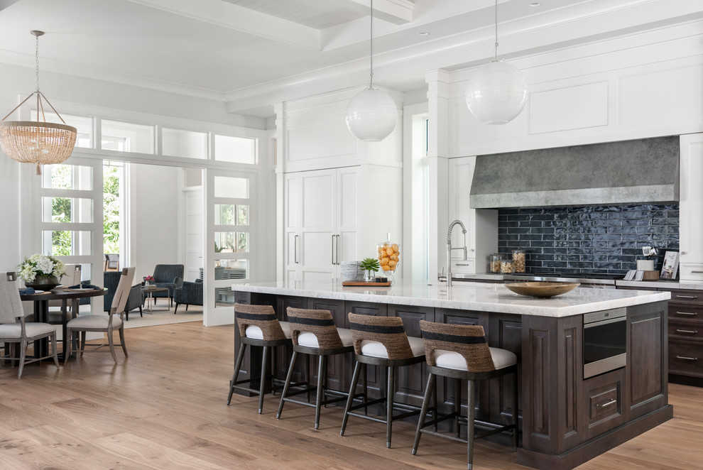 Inspiration for a tropical galley eat-in kitchen in Miami with raised-panel cabinets, dark wood cabinets, black splashback, white appliances, medium hardwood floors, with island, brown floor and white benchtop.