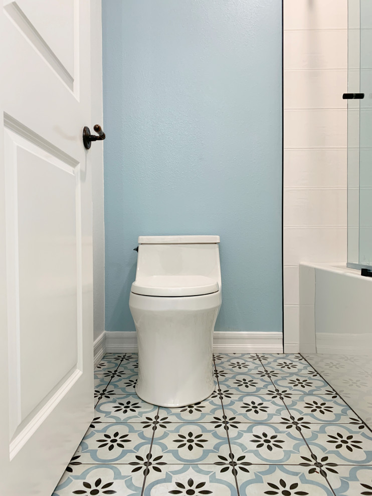 Cette photo montre une petite salle de bain tendance pour enfant avec un placard à porte shaker, des portes de placard blanches, une baignoire posée, un combiné douche/baignoire, WC à poser, un carrelage blanc, des carreaux de céramique, un mur bleu, un sol en carrelage de céramique, un lavabo encastré, un plan de toilette en quartz modifié, un sol multicolore, une cabine de douche à porte coulissante, un plan de toilette blanc, une niche, meuble double vasque et meuble-lavabo encastré.