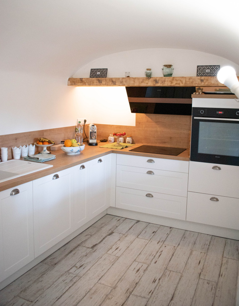 Inspiration for a mid-sized transitional l-shaped separate kitchen in Marseille with a single-bowl sink, shaker cabinets, white cabinets, laminate benchtops, brown splashback, timber splashback, black appliances, plywood floors, no island, white floor, brown benchtop and vaulted.