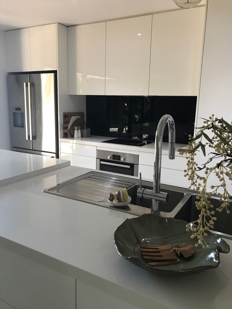 Inspiration for a mid-sized contemporary single-wall eat-in kitchen in Other with a drop-in sink, flat-panel cabinets, white cabinets, limestone benchtops, black splashback, ceramic splashback, stainless steel appliances, cement tiles, with island and grey floor.