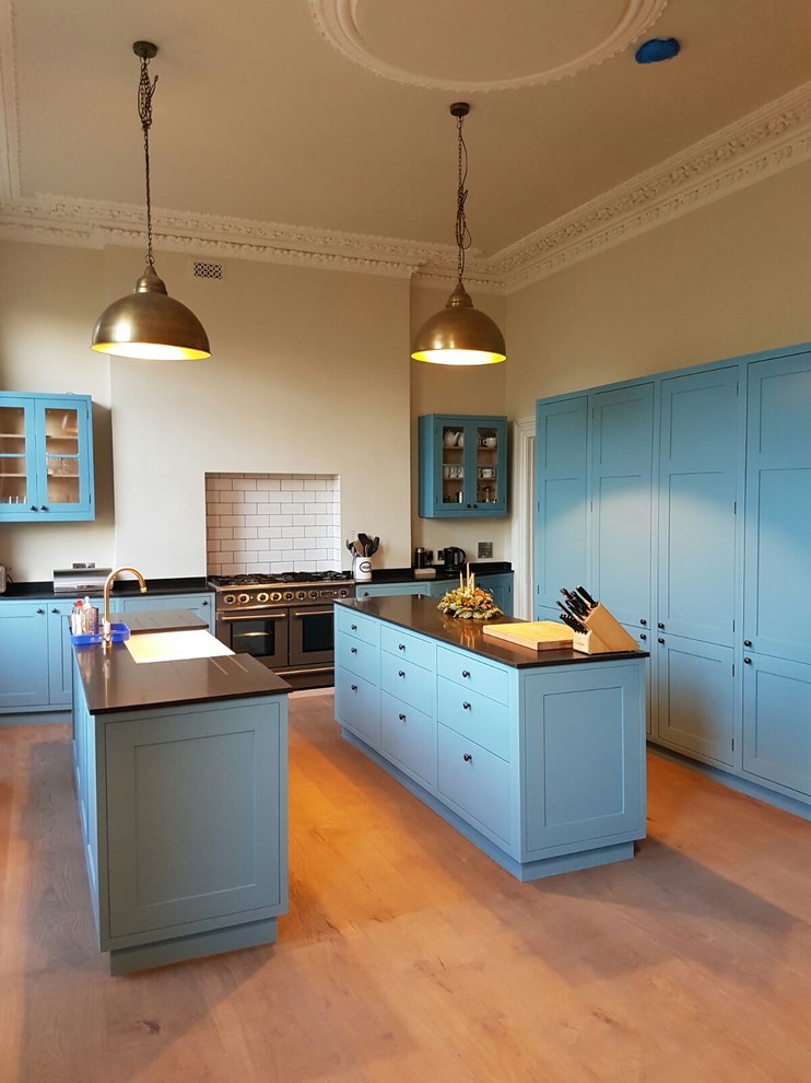Inspiration for a large contemporary u-shaped open plan kitchen in Gloucestershire with shaker cabinets, blue cabinets, medium hardwood floors, multiple islands and brown floor.