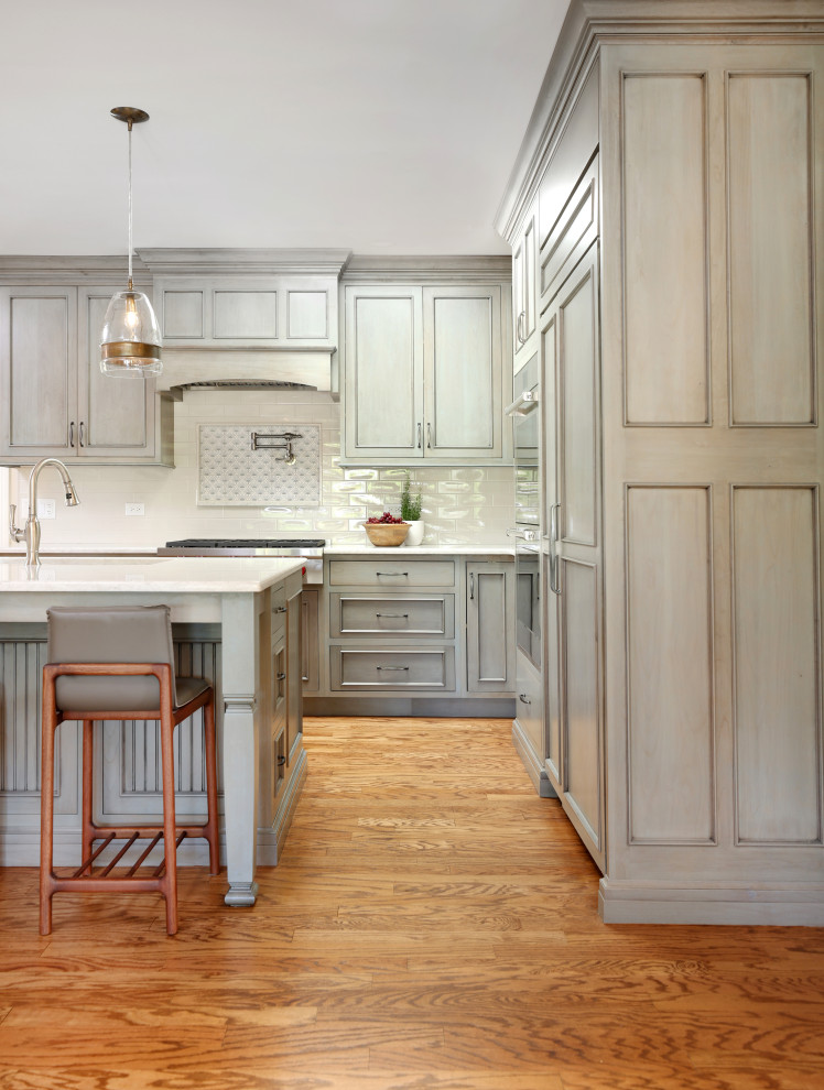 Inspiration for a large traditional l-shaped eat-in kitchen in Chicago with flat-panel cabinets, with island, an undermount sink, green cabinets, quartz benchtops, white splashback, ceramic splashback, panelled appliances and white benchtop.