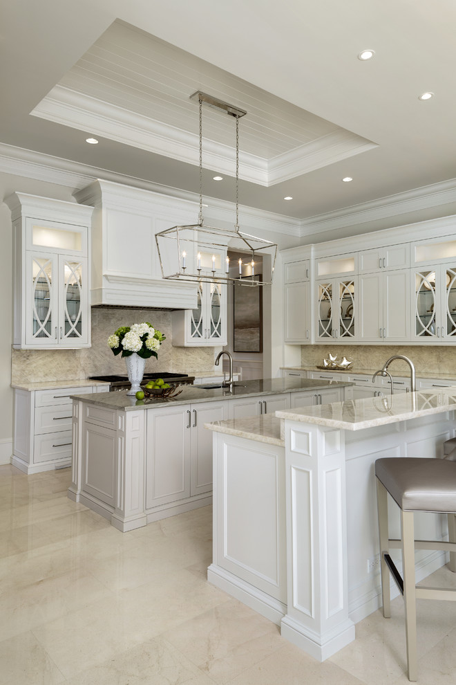 Inspiration for a large beach style eat-in kitchen in Miami with an undermount sink, recessed-panel cabinets, white cabinets, granite benchtops, white splashback, porcelain splashback, white appliances, marble floors, multiple islands and white floor.