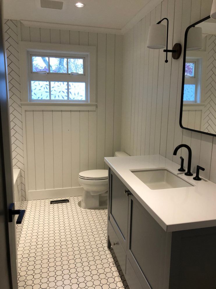Aménagement d'une salle de bain campagne avec un placard à porte shaker, des portes de placard grises, un plan de toilette en surface solide, un plan de toilette blanc, meuble simple vasque et meuble-lavabo sur pied.