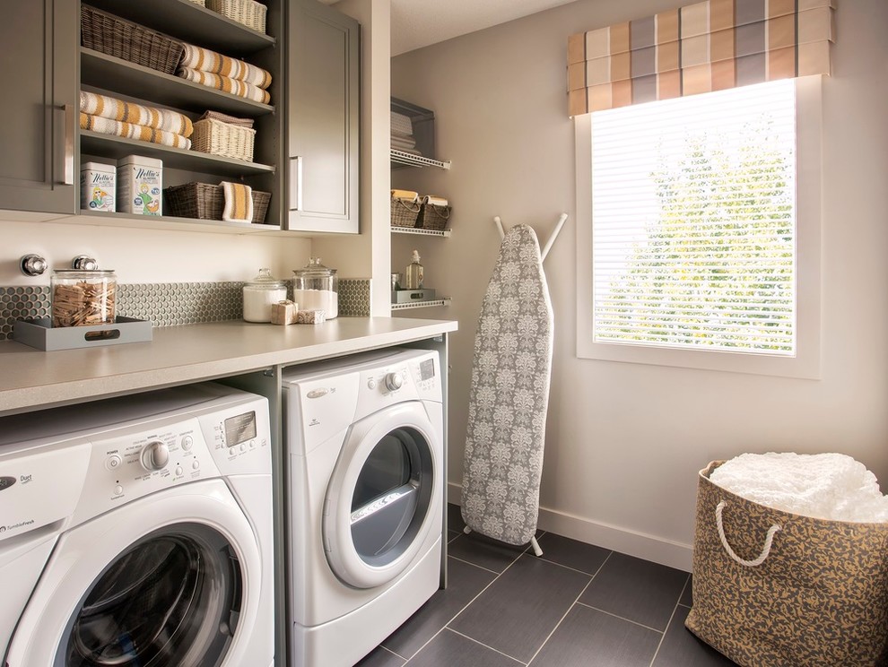 Inspiration for a transitional dedicated laundry room in Edmonton with open cabinets, grey cabinets, grey walls, a side-by-side washer and dryer and black floor.