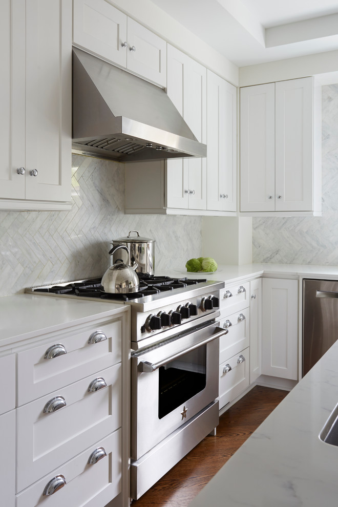 Mid-sized transitional u-shaped medium tone wood floor eat-in kitchen photo in Chicago with an undermount sink, shaker cabinets, white cabinets, solid surface countertops, blue backsplash, stone tile backsplash, stainless steel appliances and an island