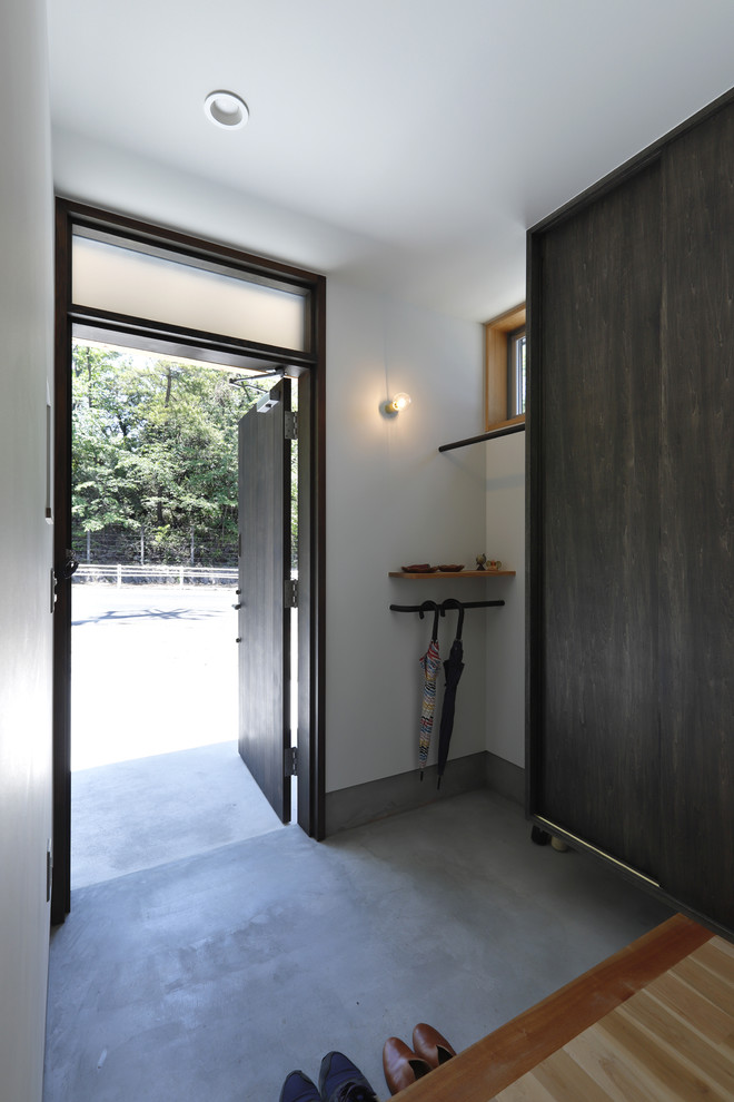 Photo of a country entryway in Other with white walls, concrete floors, a single front door, a dark wood front door and grey floor.