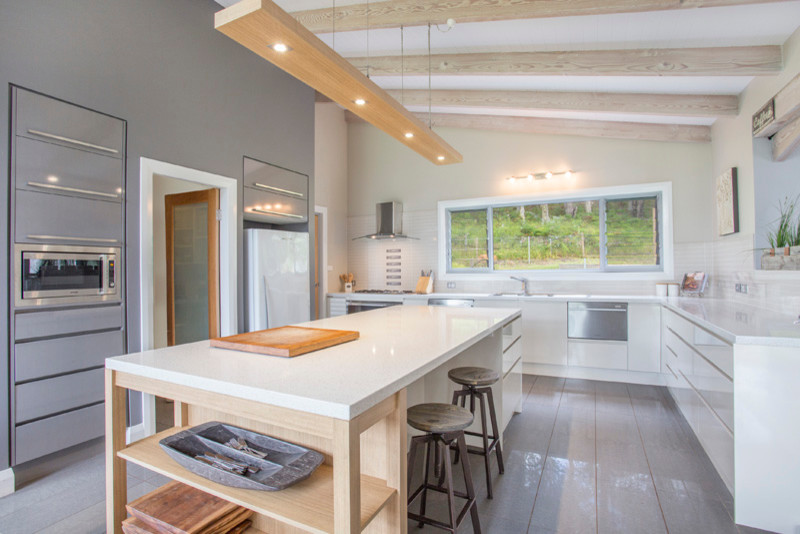 This is an example of a mid-sized country u-shaped kitchen pantry in Sydney with a double-bowl sink, flat-panel cabinets, white cabinets, granite benchtops, white splashback, ceramic splashback, stainless steel appliances, ceramic floors and with island.