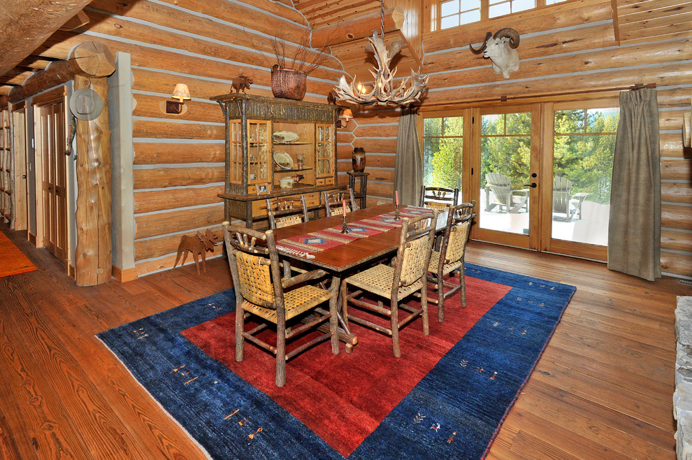 Example of a mid-sized mountain style medium tone wood floor kitchen/dining room combo design with a two-sided fireplace and a stone fireplace