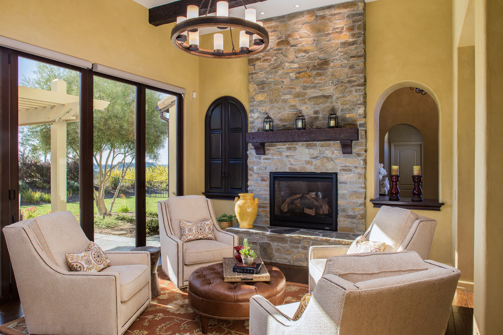 This is an example of a mediterranean enclosed living room in San Luis Obispo with yellow walls, dark hardwood floors, a standard fireplace, a stone fireplace surround and no tv.