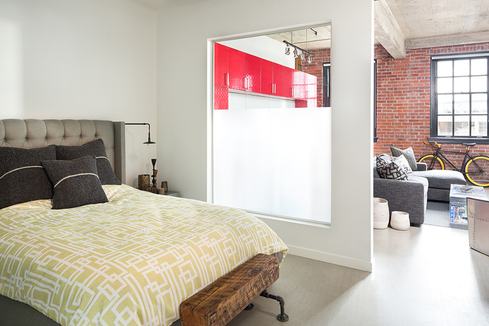 Photo of a small industrial master bedroom in Vancouver with white walls and concrete floors.