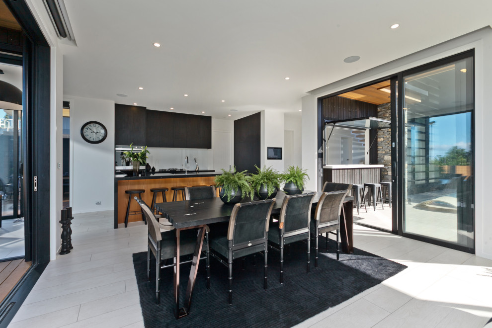 Large contemporary kitchen/dining combo in Auckland with ceramic floors, white walls and grey floor.