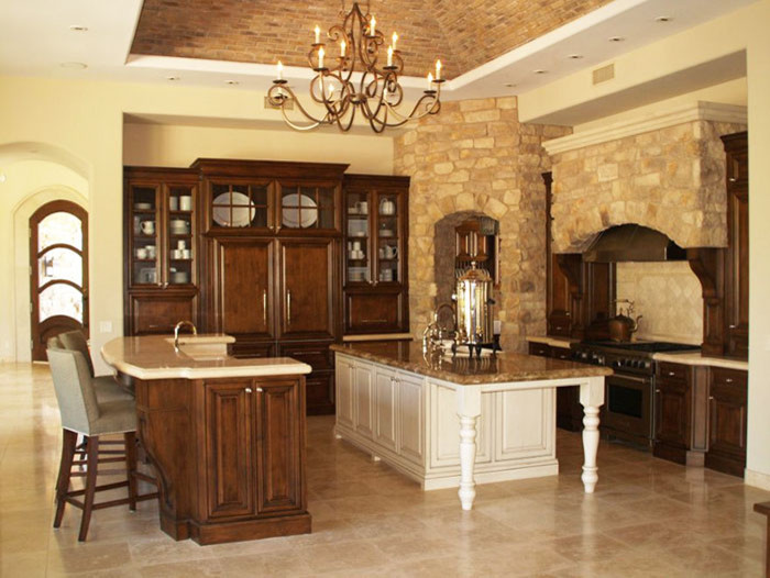 Large traditional u-shaped eat-in kitchen in Boise with a farmhouse sink, raised-panel cabinets, medium wood cabinets, granite benchtops, beige splashback, ceramic splashback, panelled appliances, travertine floors and with island.
