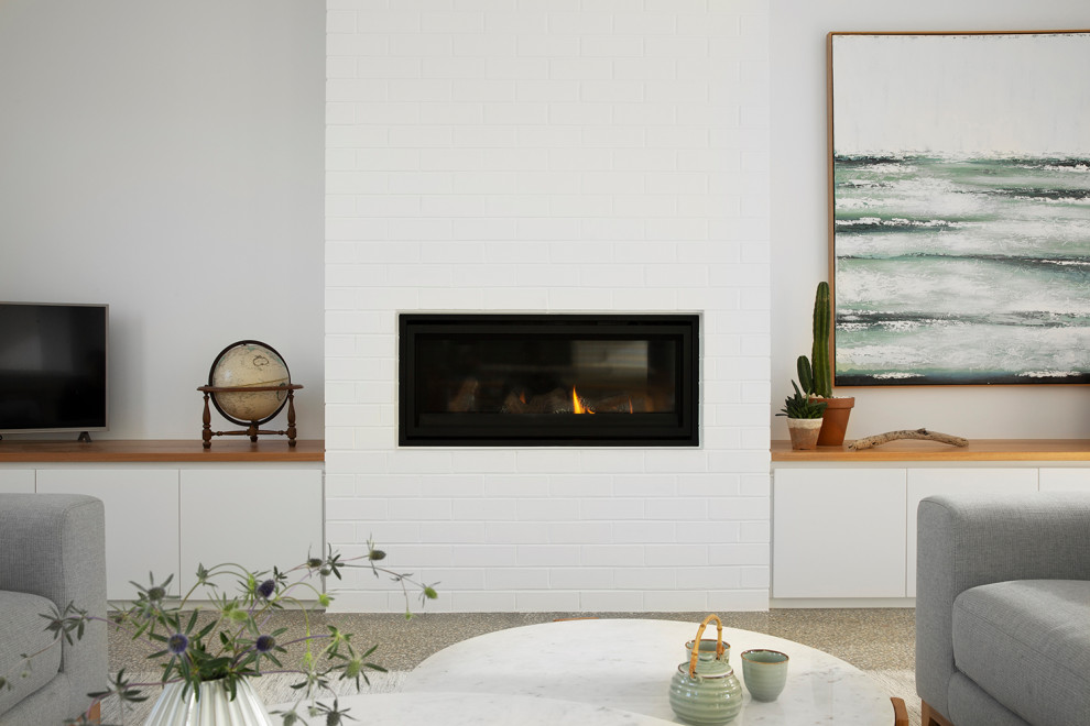 Mid-sized contemporary open concept living room in Melbourne with white walls, concrete floors, a standard fireplace, a brick fireplace surround, a corner tv, grey floor and brick walls.