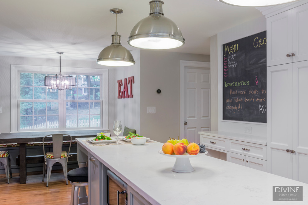 Photo of a mid-sized eclectic galley eat-in kitchen in Boston with an undermount sink, shaker cabinets, white cabinets, quartz benchtops, white splashback, subway tile splashback, stainless steel appliances, medium hardwood floors, with island and brown floor.