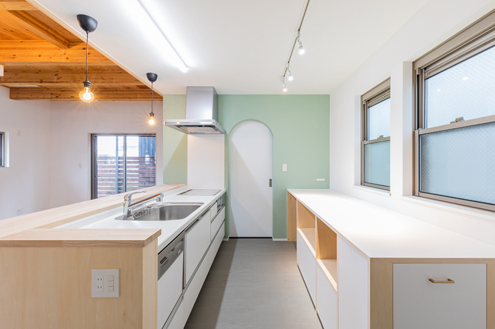 Cette image montre une cuisine ouverte nordique avec des portes de placard blanches, une crédence blanche et un plan de travail marron.