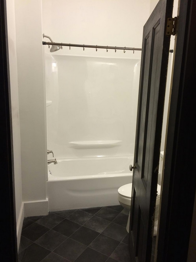 Small traditional bathroom in Indianapolis with an integrated sink, a shower/bathtub combo, black tile and white walls.