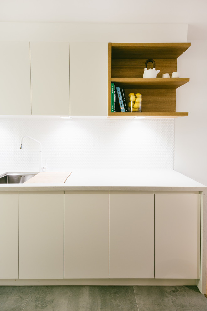 This is an example of a mid-sized contemporary galley separate kitchen in Adelaide with an undermount sink, flat-panel cabinets, white cabinets, quartz benchtops, white splashback, mosaic tile splashback, stainless steel appliances, porcelain floors, no island and grey floor.