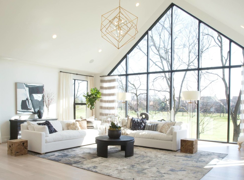 Expansive transitional open concept living room in Indianapolis with white walls, light hardwood floors, a standard fireplace, a concrete fireplace surround, a wall-mounted tv and brown floor.