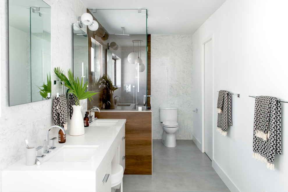 This is an example of a large contemporary master bathroom in Miami with flat-panel cabinets, white cabinets, an alcove shower, a two-piece toilet, gray tile, white walls, an undermount sink, grey floor, a hinged shower door, white benchtops, a double vanity and a built-in vanity.