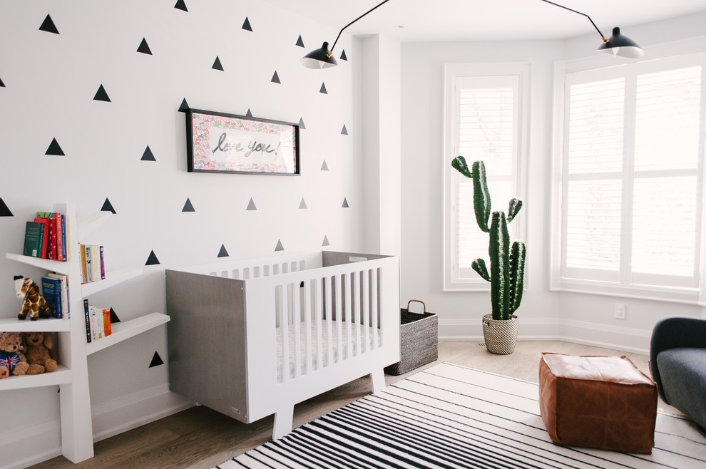 Mid-sized contemporary gender-neutral nursery in Toronto with grey walls, light hardwood floors and brown floor.