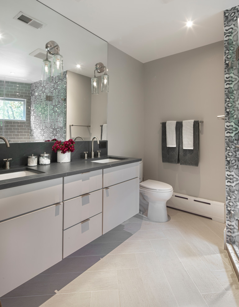 Inspiration for a contemporary master bathroom in DC Metro with flat-panel cabinets, white cabinets, a corner shower, medium hardwood floors, an undermount sink, soapstone benchtops, grey benchtops, a double vanity, a floating vanity, a one-piece toilet, beige floor, a hinged shower door, grey walls and a shower seat.