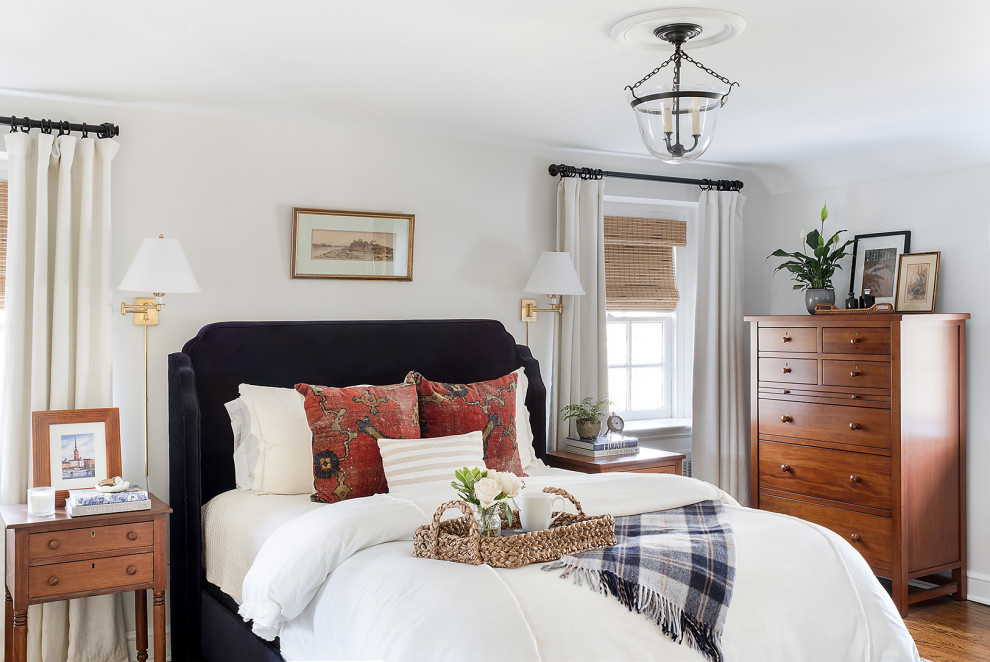 Traditional bedroom with white walls, medium hardwood floors and brown floor.