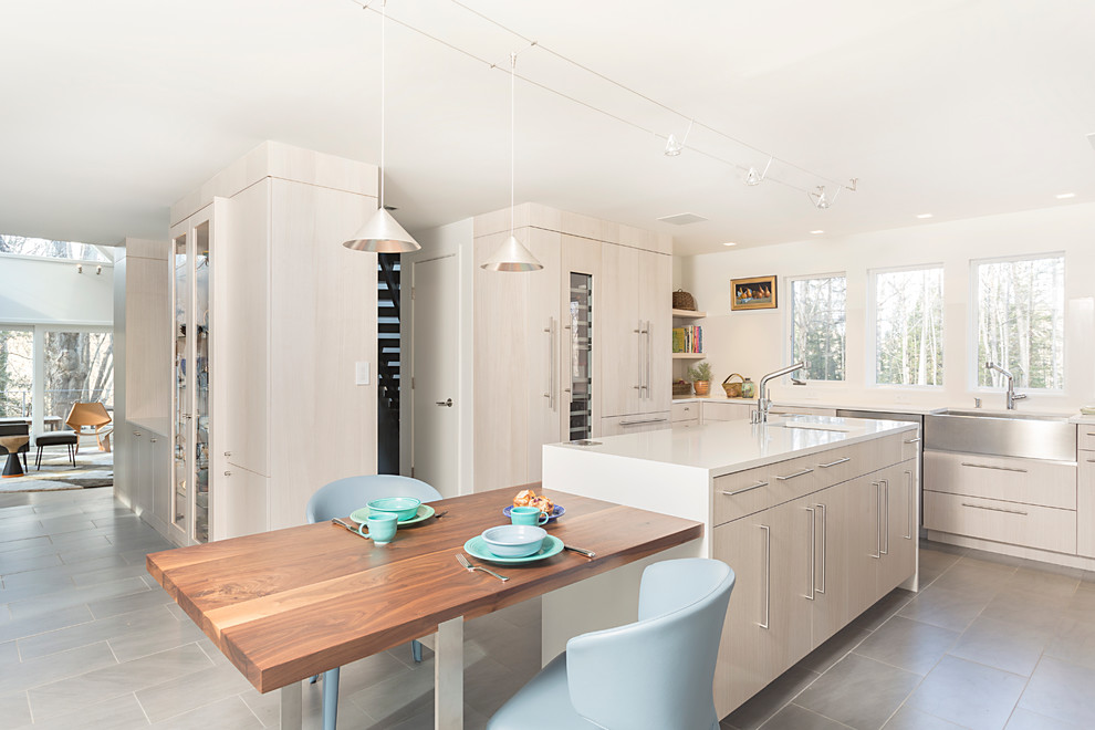 Photo of a mid-sized scandinavian u-shaped eat-in kitchen in New York with a farmhouse sink, flat-panel cabinets, light wood cabinets, quartz benchtops, panelled appliances, porcelain floors and with island.